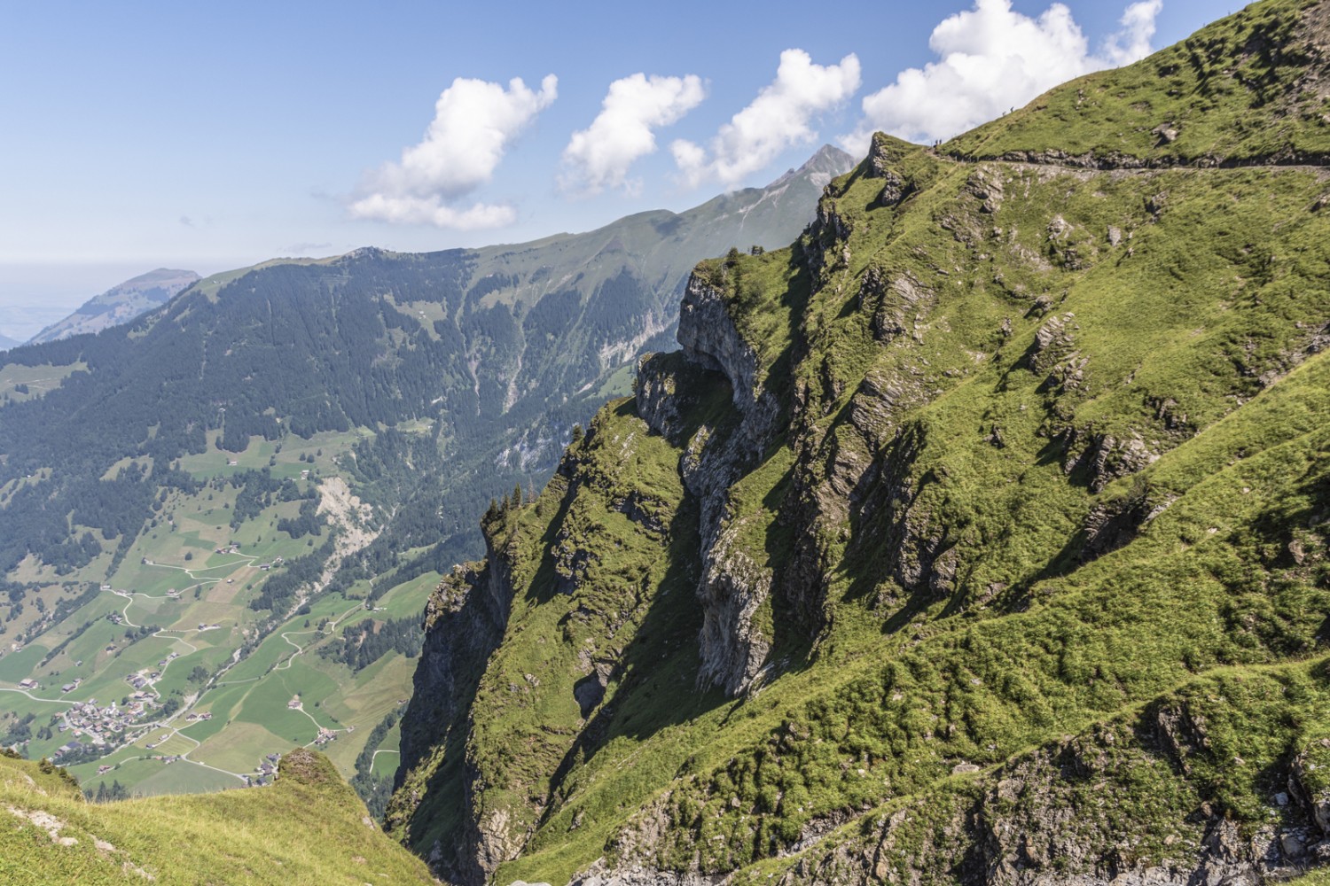 Les randonneuses et randonneurs sur la crête semblent tout petits. Lorsque le terrain est escarpé, le sentier est bordé d’une clôture. Photo: Franz Ulrich