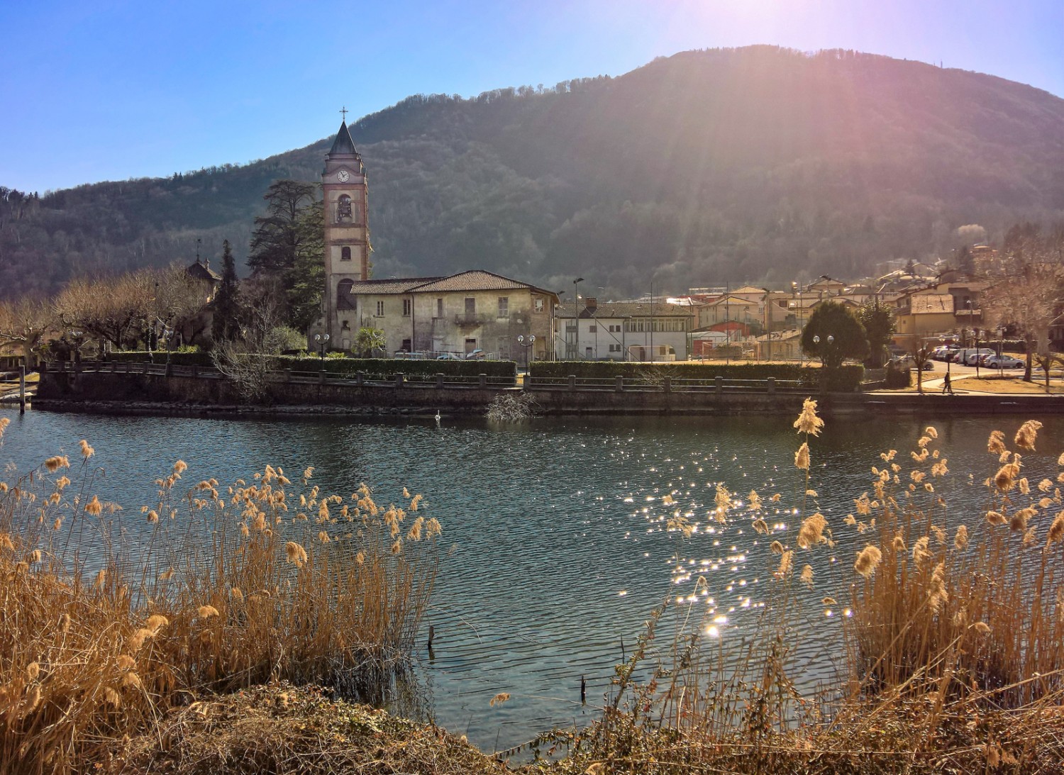 Hier ist Italien nur noch einen Steinwurf entfernt: Von Torrazza sieht man über den schmalen Arm des Luganersees zur Dorfkirche von Lavena hinüber. Bild: Andreas Staeger